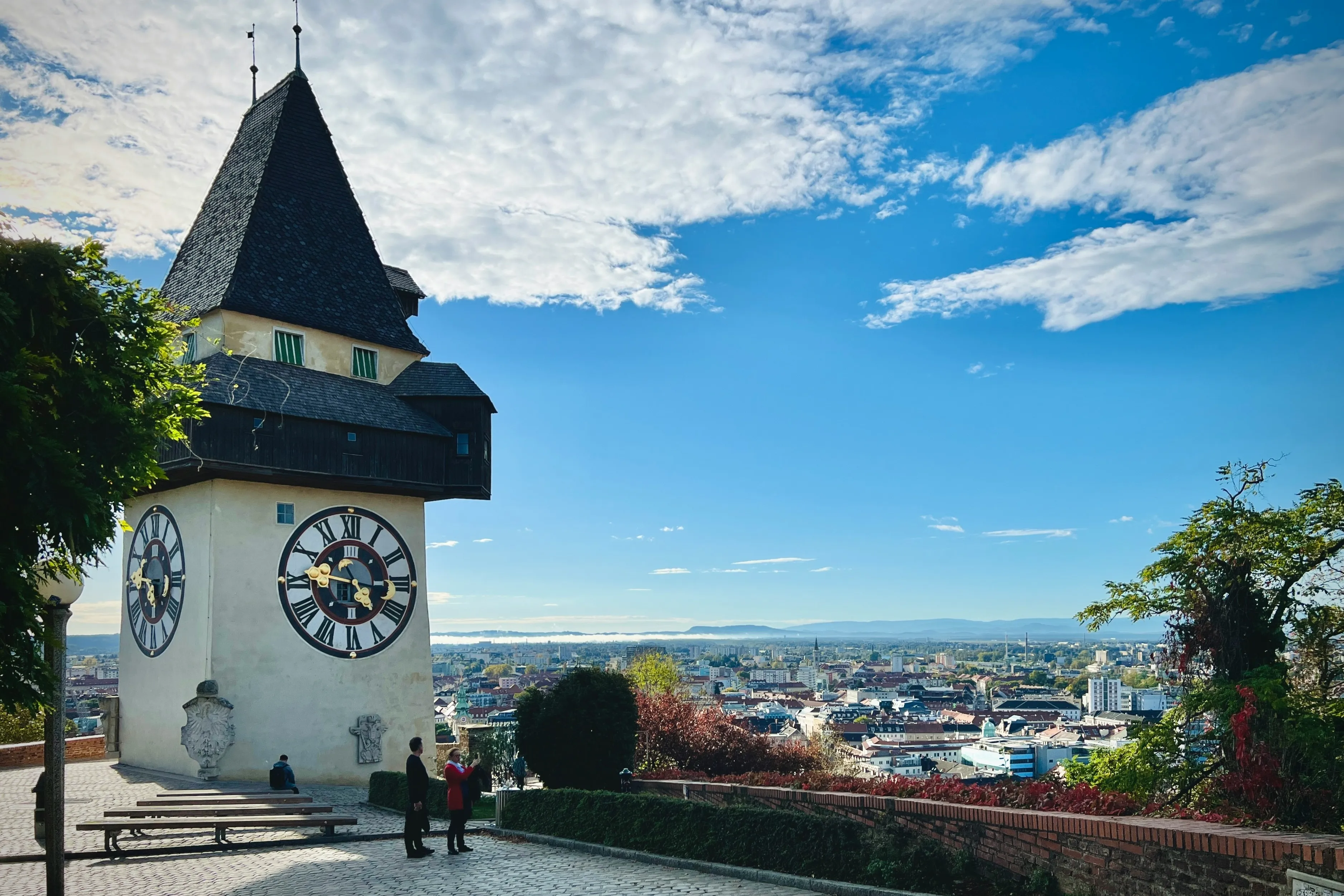 Uhrturm auf dem Schlossberg in Graz, daneben der Blick über die Stadt im Herbst