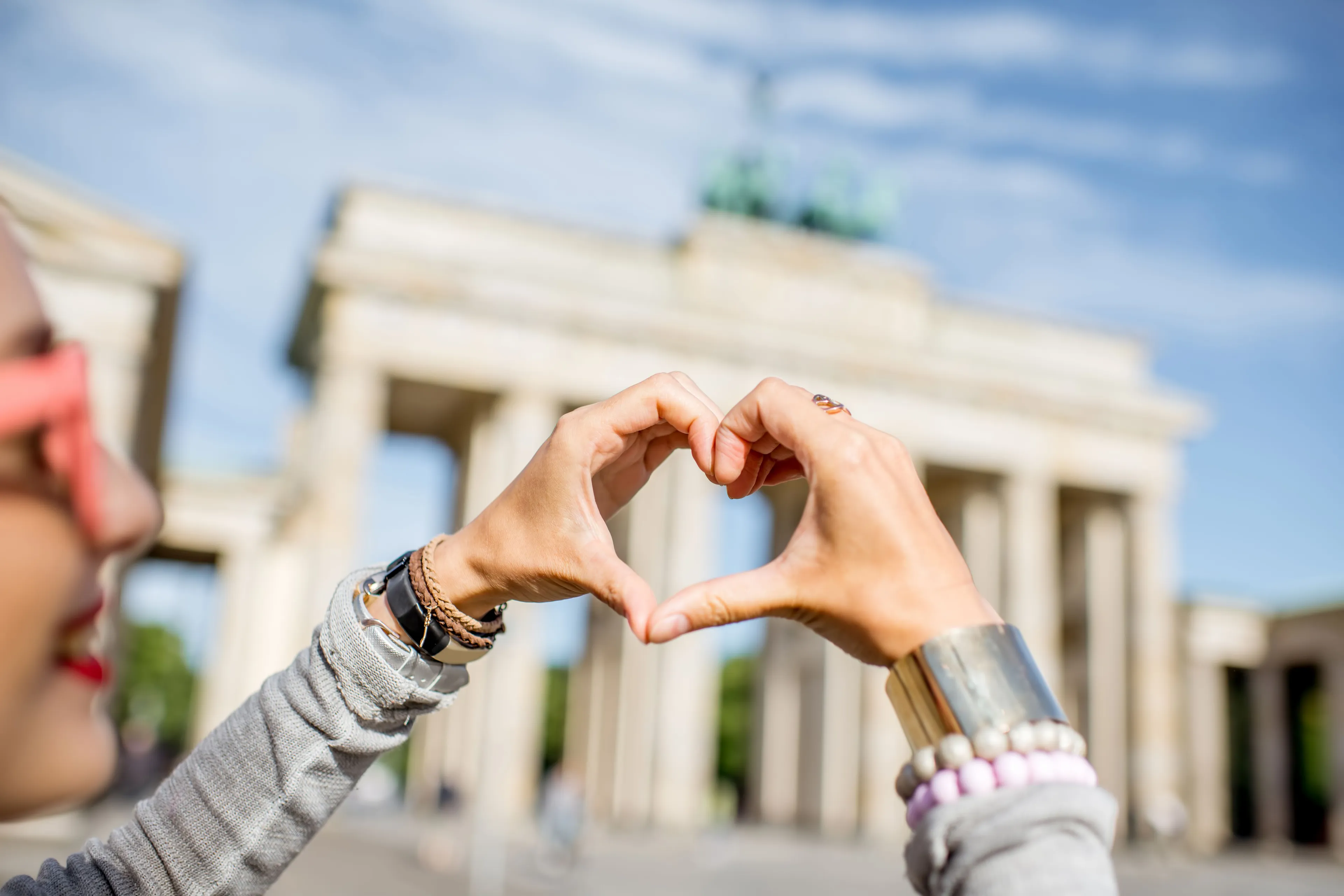 Woman forming a heart with her hands in front of the Brandenburg Gate