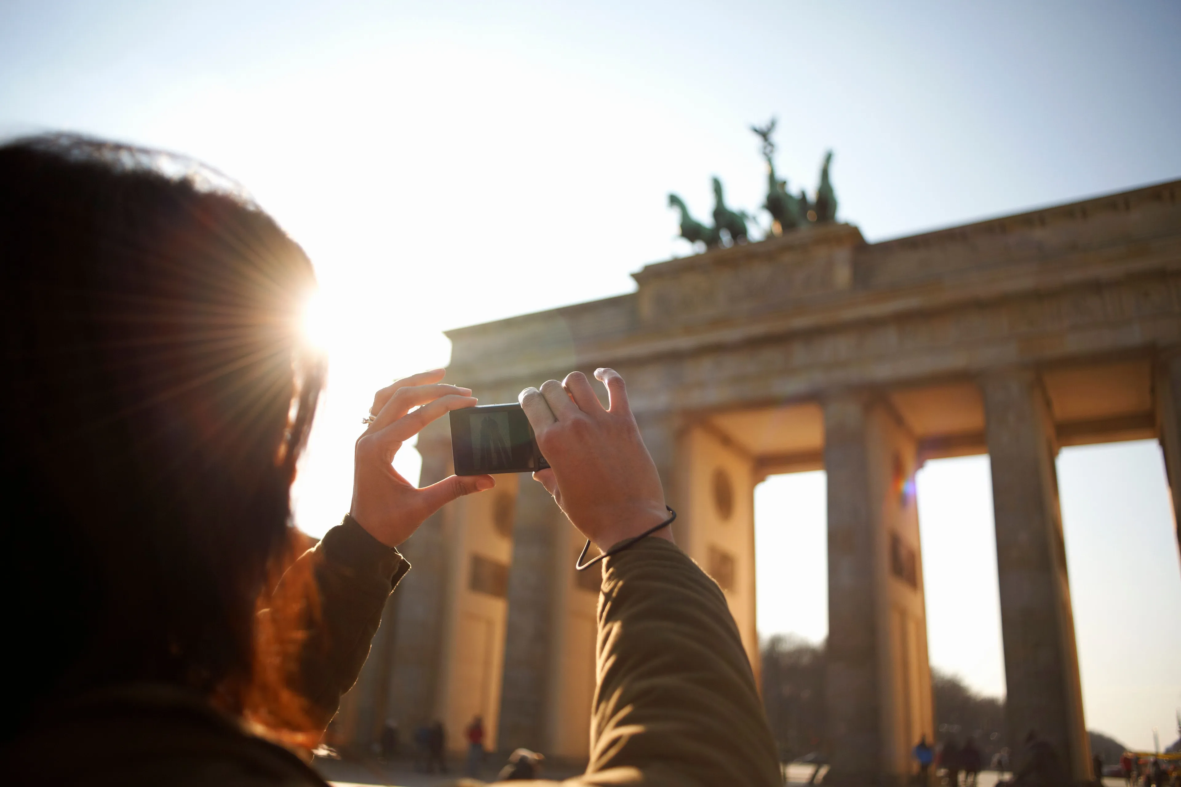 Touristin fotografiert das Brandenburger Tor mit dem Handy