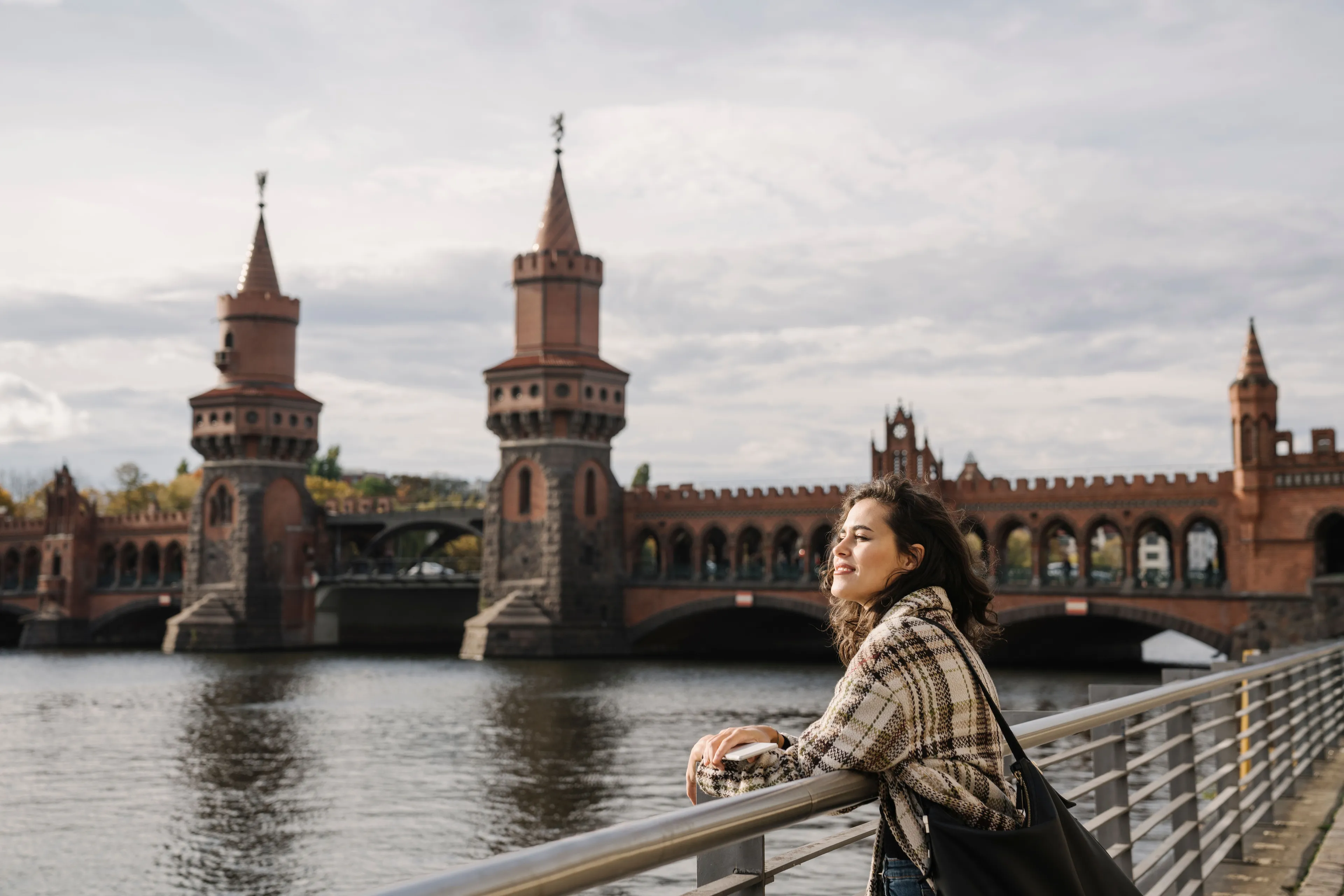 Smiling woman by the Spree in front of the Oberbaum Bridge