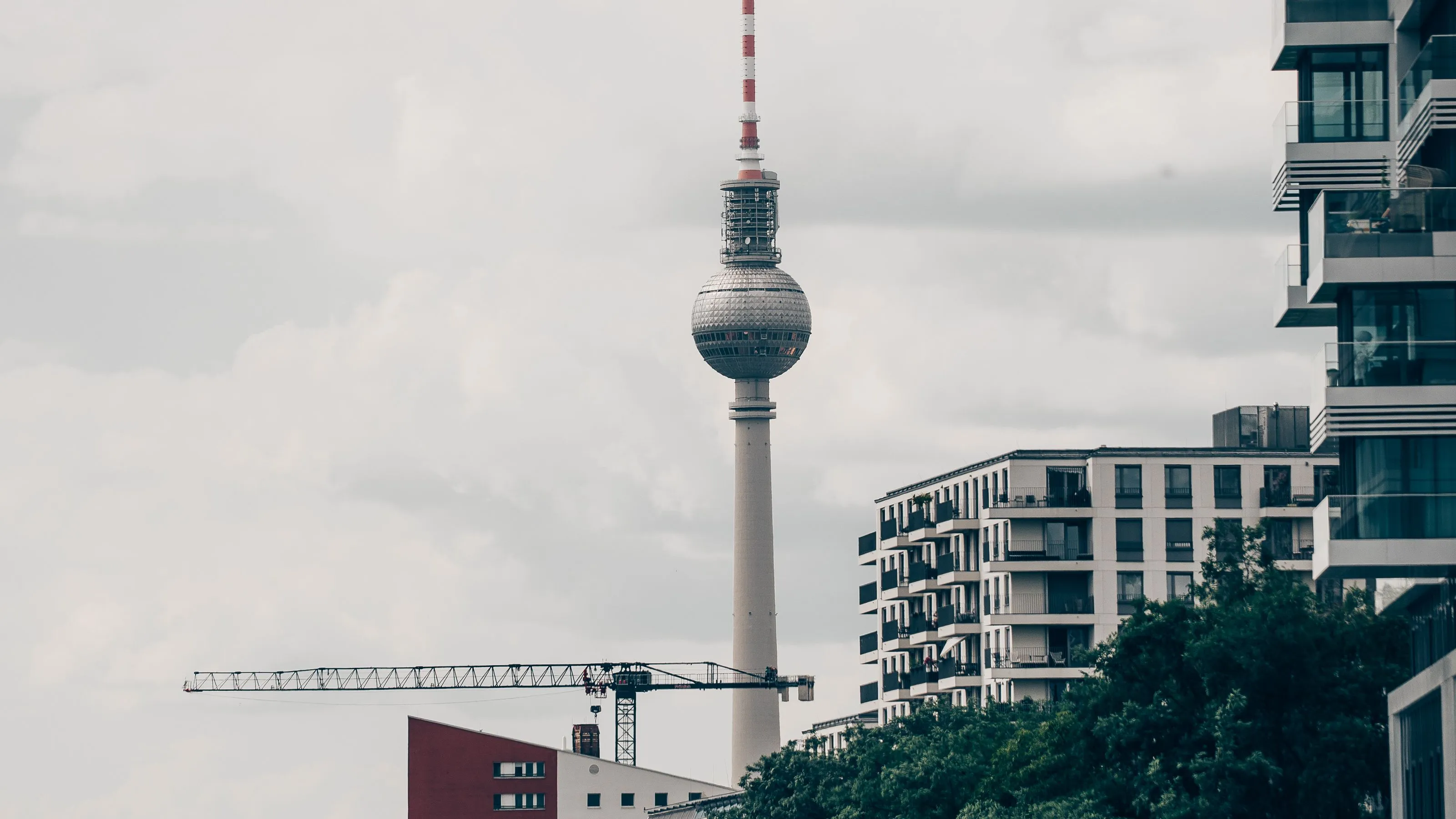 The Berlin TV tower seen along the Spree, with modern apartment buildings and trees