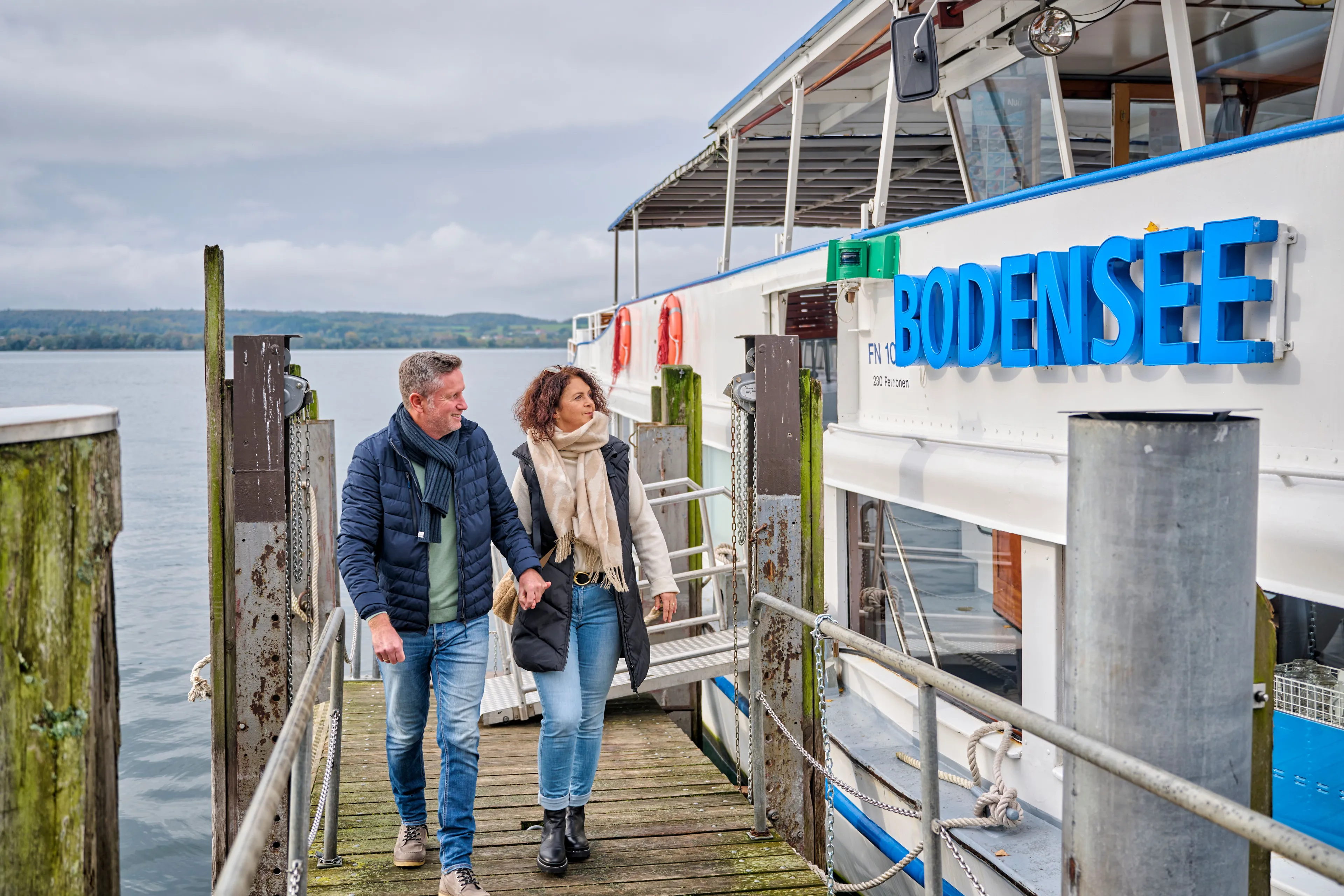 Couple on a jetty next to a passenger ship on Lake Constance