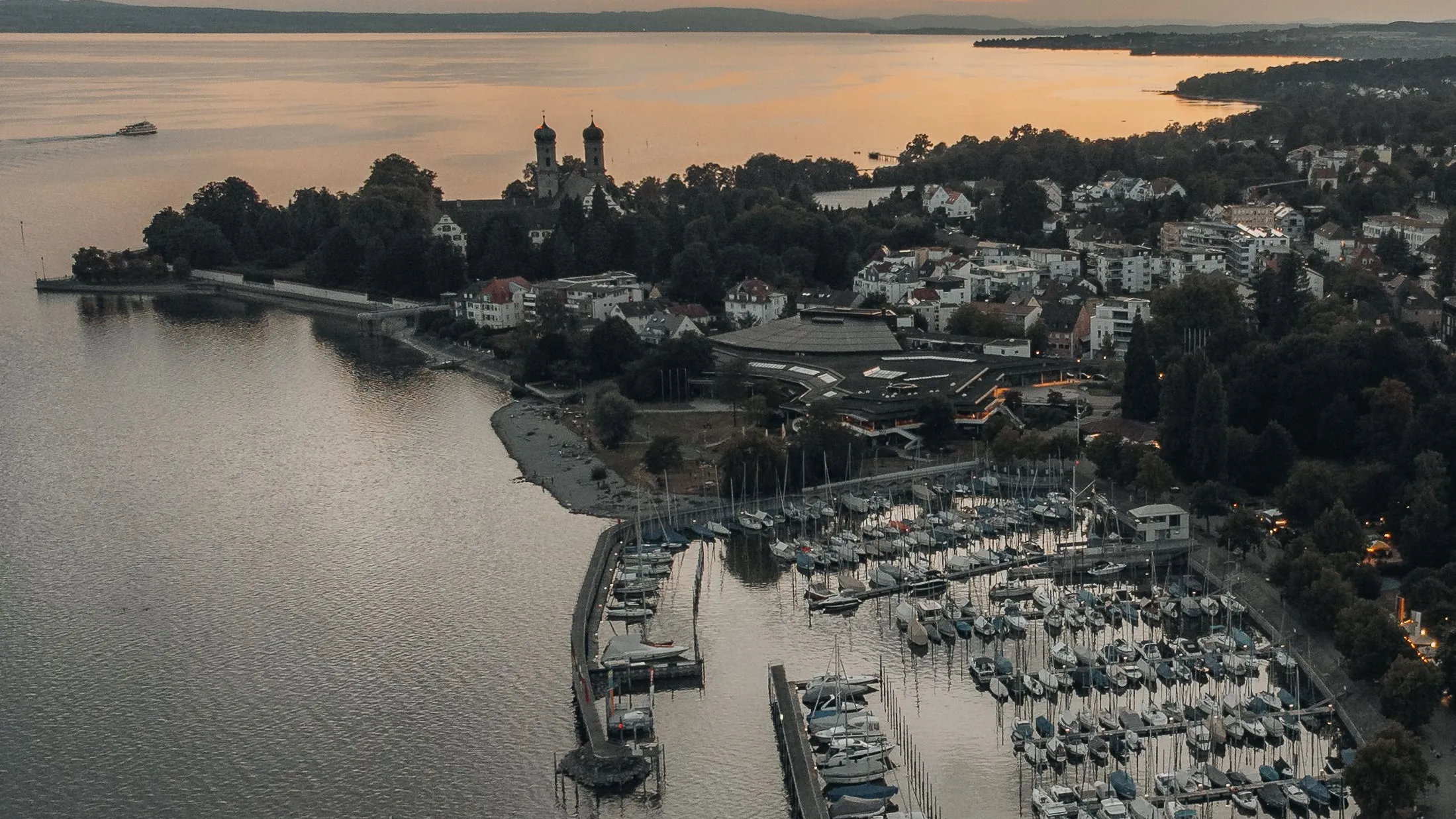 Friedrichshafen at dusk from above: the marina, the Schlosskirche and Lake Constance