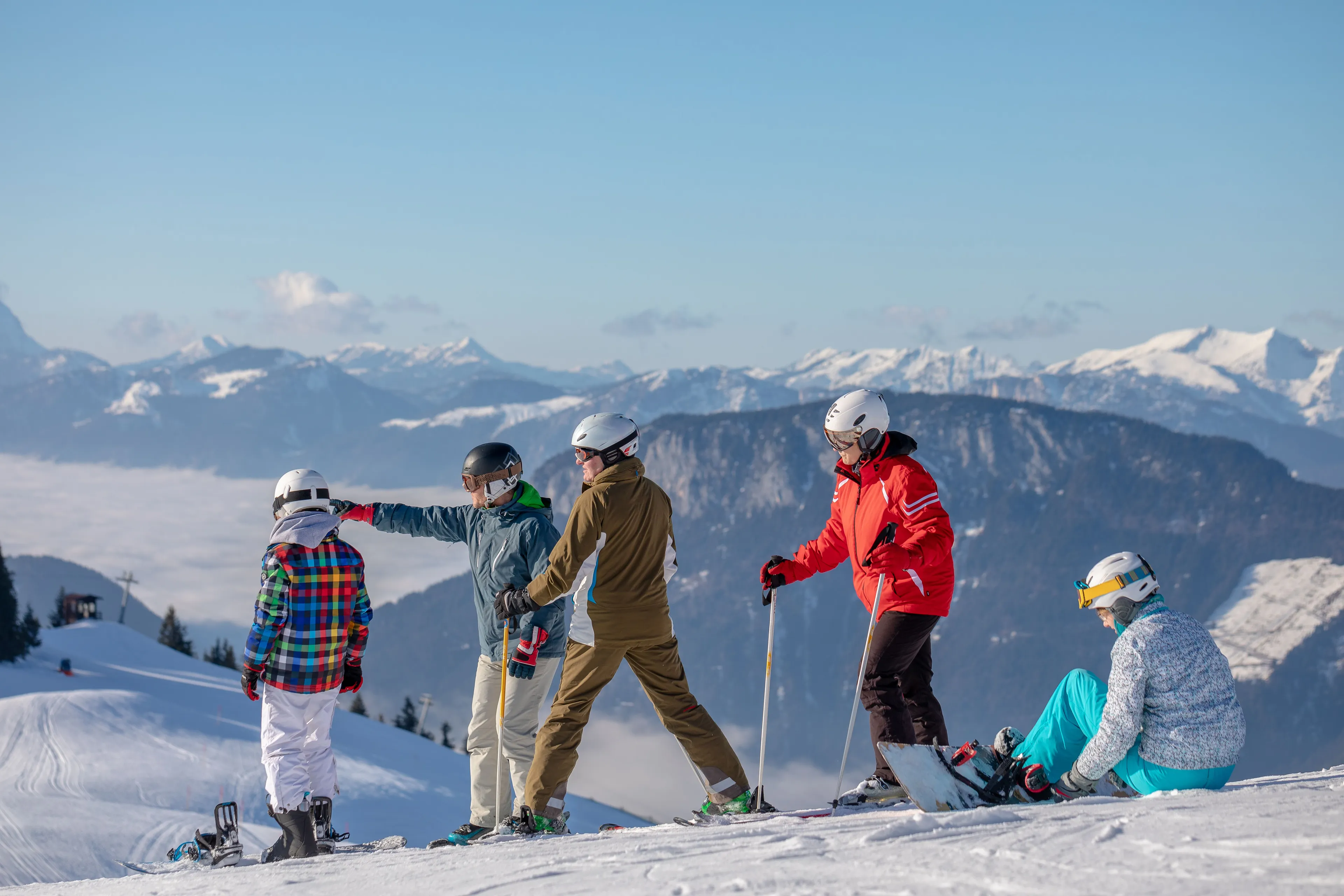Gruppe von Skifahrern und ein Snowboarder auf einer Piste